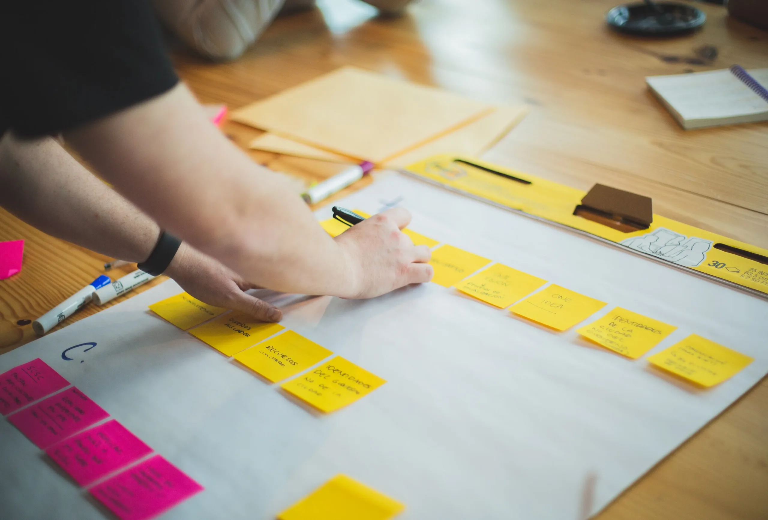 A woman organizing notes on post-its and sticking them to a large sheet of paper.