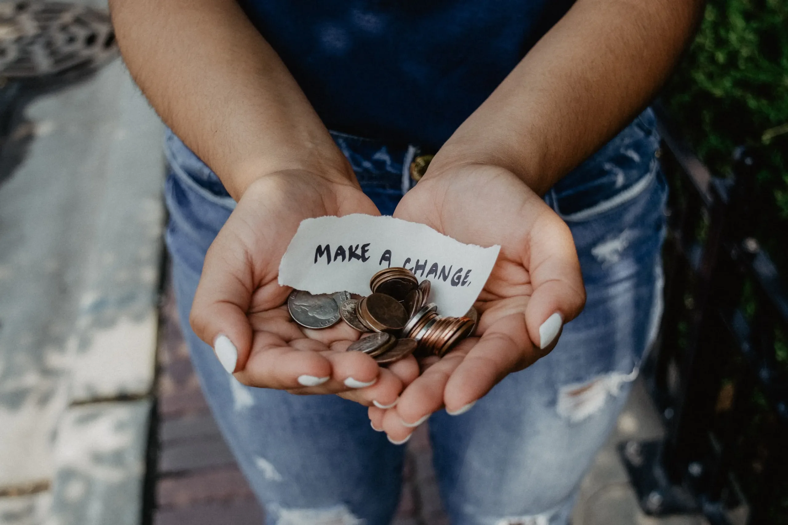 Woman cupping her hands together holding U.S. coins and a strip of paper that says "make a change."